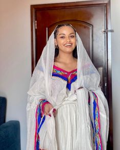 a woman wearing a white dress and veil standing in front of a door with her hands on her hips