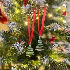 two ornaments hanging from the top of a christmas tree with red and green ribbons on it