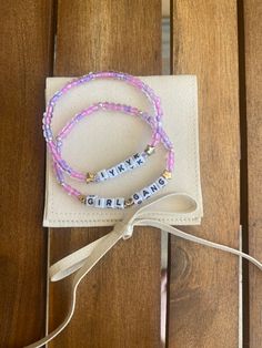 two bracelets with words on them sitting on top of a wooden table