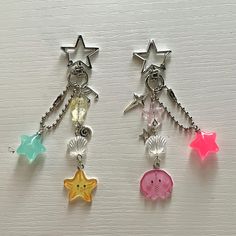 three different colored stars hanging from chains on a white surface with beads and charms attached to them