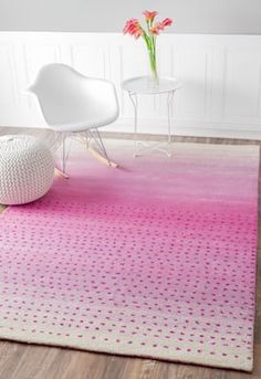 pink and white rug with polka dots on the floor in front of a chair next to a flower vase