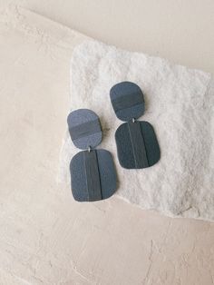 two pairs of earrings sitting on top of a pile of snow