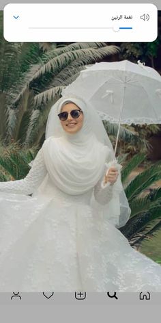 a woman in a white wedding dress holding an umbrella and smiling at the camera with palm trees behind her