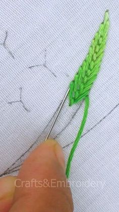 someone is stitching on the fabric with green thread and needle in front of them