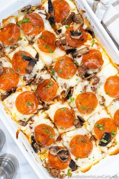 a pizza casserole with mushrooms, cheese and sauce in a white baking dish