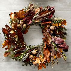 a wreath with autumn leaves and berries hanging on a wall