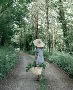 a woman walking down a dirt road carrying a basket