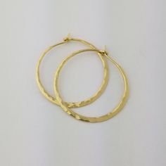 "Gorgeous Hammered Solid 18k Hoops made from 16 gauge (1.3mm) wire. 1.25\" Size photographed; 2\" size in 14k yellow gold shown in video METAL: Solid 18k Yellow Gold WIRE GAUGE/DIAMETER: 16 gauge (1.3mm) wire - Currently the thickest wire I offer EAR WIRE THICKNESS: Due to the thickness of the wire, the ear wire portion of the hoops will be tapered to approximately 18g, which is slightly thicker than standard ear wire thickness HAMMERED EFFECT: Each earring is made as a mirrored pair and the tex Hand Forged Earrings For Anniversary, Elegant Gold Hoop Earrings In Recycled Gold, Hammered Hoop Earrings For Anniversary, Hammered 14k Yellow Gold Jewelry, Elegant Hammered Hoop Earrings For Anniversary, 14k Yellow Gold Hammered Jewelry, Hammered 14k Gold-filled Hoop Earrings, Hammered Gold Plated Hoop Jewelry, Hammered Gold-plated Hoop Jewelry