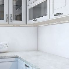 a white kitchen with marble counter tops and cabinets in the backround, along with two bowls on the counter