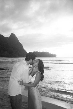 a man and woman kissing on the beach