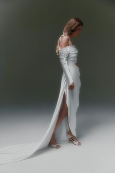 a woman in a white dress is standing with her legs spread out and looking down