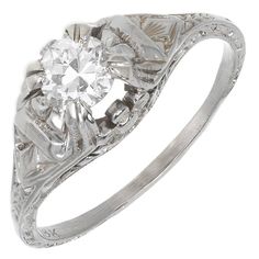 an antique style diamond ring with filigrees on the shoulders and sides, in white gold