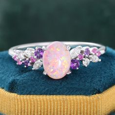 ✧ Made to Order: Handcrafted specifically for you.  ✧ Variety of Metal Options: Choose from 925 sterling silver with gold plating, or opt for 14k or 18k solid gold.  ✧ Customizations Available: Personalize every detail to make it uniquely yours.  This pink opal engagement ring features a stunning oval opal at its center, radiating a beautiful play of colors that shimmer with movement. The opal is elegantly surrounded by clusters of pink sapphire, amethysts, and sparkling moissanites, creating a vibrant contrast. The polished rose gold band is designed to flow gracefully, enhancing the overall aesthetic with a touch of sophistication.      · Center Stone: 6*8mm Oval Cut Lab Pink Opal - Approx. 1.3CT     · Accent Stones: Marquise & Round Pink Sapphire & Amethyst & M Luxury Opal Ring With Accent Stones For Gift, White Gold Amethyst Ring With Gemstone Accents For Gift, Gift White Gold Amethyst Ring With Gemstone Accents, White Gold Opal Gemstone Ring For Gift, Luxury White Gold Opal Ring As Gift, Gift White Gold Opal Gemstone Ring, Luxury White Gold Opal Ring Gift, Luxury Sterling Silver Cluster Ring With Gemstones, Sterling Silver Multi-stone Opal Ring As Gift