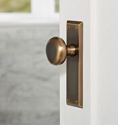 an open door with a brass handle on the outside and marble walls in the background