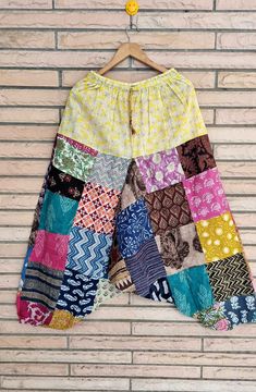 a colorful patchwork skirt hanging on a brick wall