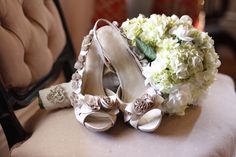 wedding shoes and bouquet sitting on top of a chair in front of a chair cushion