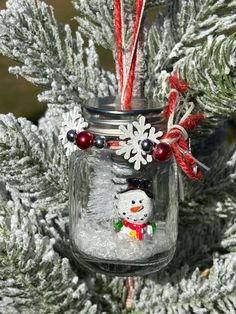 a mason jar with a snowman ornament hanging from it's side