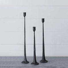 three tall black candlesticks sitting next to each other