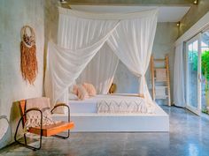 a white bed sitting inside of a bedroom next to a window