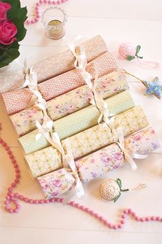 a bunch of rolls of fabric sitting on top of a table next to flowers and beads