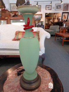 a large green vase sitting on top of a table in a room filled with furniture