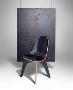 a black chair sitting in front of a painting on a gray wall with chains hanging from it's sides