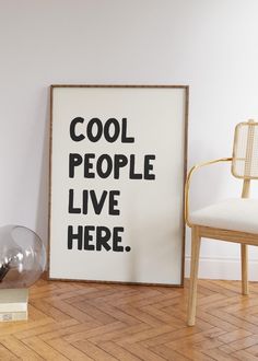 a poster that says cool people live here on the wall next to a chair and lamp