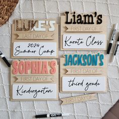 wooden name tags with names on them sitting on a bed next to markers and pens