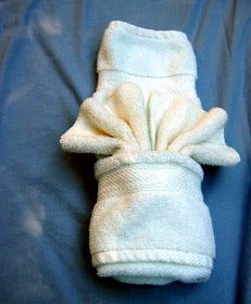 a white towel wrapped in a bow on top of a blue cloth covered bed sheet