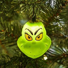 a green ornament with an angry face on it hanging from a christmas tree