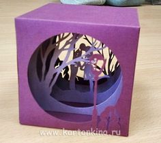 a purple box with a paper cut out of it on top of a wooden table