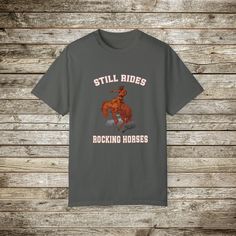 Check out my funny new wild west rodeo cowboy graphic T-Shirt, Done in the Retro Style of the 80s and 90's, this graphic western shirt, pokes gentle fun at the manly and bravery it takes to ride a bucking bronc horse. Every now and then you have to step back and say wow! Look at that guy ride! and wonder... How many rocking horse the went through as a toddler... ☺️??? Gotta love a cowboy! This super comfy comfort color tee has a relaxed fit and the cotton is soft and durable. This will make a great gift for the guy with a sense of humor! Comfort Colors Tshirts: About the Designer of FlooredByArt Studios: ☀️As an artist I try to capture the beauty of nature and the spirit of beloved animals with these stunning archival quality prints. Each design is crafted using cutting-edge digital artist Western Style Relaxed Fit Graphic T-shirt, Western Style Relaxed Fit T-shirt With Graphic Print, Western Style Relaxed Fit T-shirt With Screen Print, Western Style Screen Print T-shirt For Western-themed Events, Casual Graphic Print Shirt For Ranch, Graphic Print T-shirt For Western-themed Events, Relaxed Fit, Relaxed Fit Graphic T-shirt For Western-themed Events, Western Style Short-sleeved Screen Print T-shirt, Crew Neck Letter Print Shirt For Rodeo