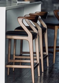 the chairs are lined up on the wooden floor in front of the counter top and bar stools