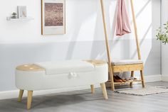 a white bench sitting in front of a mirror on top of a wooden floor next to a plant