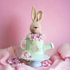 a cake shaped like a rabbit sitting in a teacup with flowers on the side