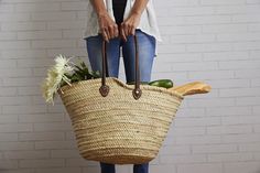 a woman holding a large woven basket with vegetables in it