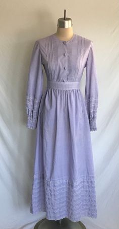 Darling 1970's purple cotton eyelet lace trimmed prairie dress with pockets! Dress is a maxi length with long sleeves, tie back at waist, button down front and buttons that look like jelly beans! Dress zips up the back with a plastic zipper. Dress has a Victorian Gunne Sax look to it and fits easily into the cottagecore style.  Dress is clean and in excellent condition!  No label: appears to have been skillfully handmade!  Measurements: would best fit a modern size XS  Bust= 34" Waist= 25" Hip= Cotton Victorian Dress For Dressmaking, Fitted Cotton Prairie Dress For Daywear, Cotton Prairie Dress For Daywear, Cotton Victorian Cottagecore Dress For Daywear, Cotton Victorian Dress With Buttons For Daywear, Cotton Victorian Dress With Long Sleeves In Cottagecore Style, Cotton Long Sleeve Victorian Cottagecore Dress, Cottagecore Victorian Cotton Dress For Daywear, Spring Prairie Style Cotton Dress