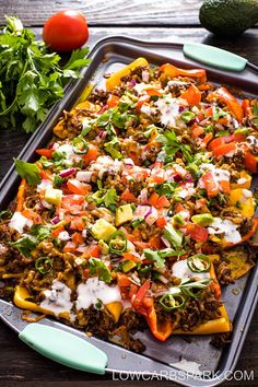 a tray filled with taco salad next to tomatoes and avocado