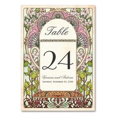 a wedding table number card with an ornate frame and floral design in green, gold and white