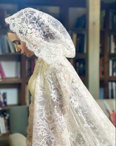 a mannequin wearing a white veil in front of a bookshelf