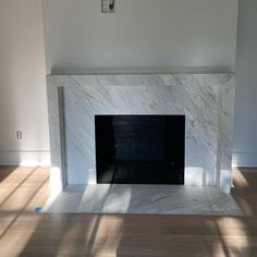 an empty room with a fireplace in the middle and no one around it on the floor