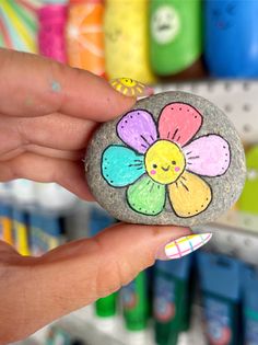 a hand holding a rock with a painted flower on it