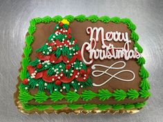 a decorated christmas cake with the words merry christmas written on it and a small tree