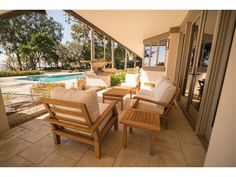 an outdoor patio with chairs and tables next to a swimming pool