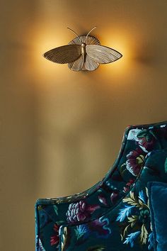 a blue chair sitting in front of a wall mounted moth light on it's side