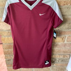 a maroon and white shirt hanging on a brick wall