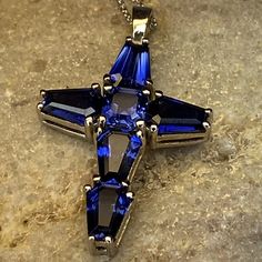 "Blue Sapphire Cross Pendant with trapezoid stones #7035 -Approximate total carat weight: 5.50ctw diamond equivalent -Center Stone Size: approx. 0.50ct/each diamond equivalent -Center Stone Shape: Asscher cut 5x5mm -Gem Type: lab created blue sapphire -Stone Clarity: VS2 -Stone Color: F -Moh's Scale: 9 hardness -Stone Size: approx. 1.00ct/each diamond equivalent -Stone Shape: 5 Elongated trapezoid 7x5mm each -Gem Type: lab created blue sapphire -Stone Clarity: VS2 -Stone Color: F -Moh's Scale: 9 Blue Emerald Cut Gemstone Necklace, Blue Baguette Cut Fine Jewelry, Blue Cubic Zirconia Gemstones For Gift, Blue Cubic Zirconia Gemstones As Gift, Blue Emerald Cut Gemstones For Gifts, Blue Emerald Cut Gemstone As Gift, Blue Baguette Cut Necklaces For Gifts, Blue Diamond Cut Pendant Jewelry, Sapphire Jewelry With Diamond Baguette Cut