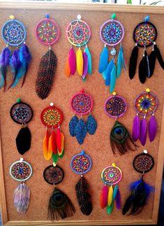 a wooden frame with many different colored feathers on it and beads hanging from the sides