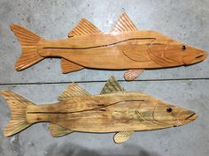 two wooden fish are sitting on the floor