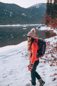 a woman walking in the snow with a backpack